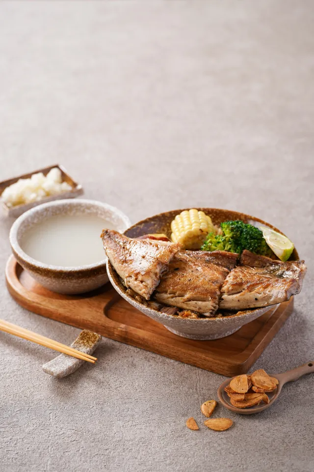 香煎魚排蓋在蛋炒飯上，旁邊是雞湯與醃蘿蔔